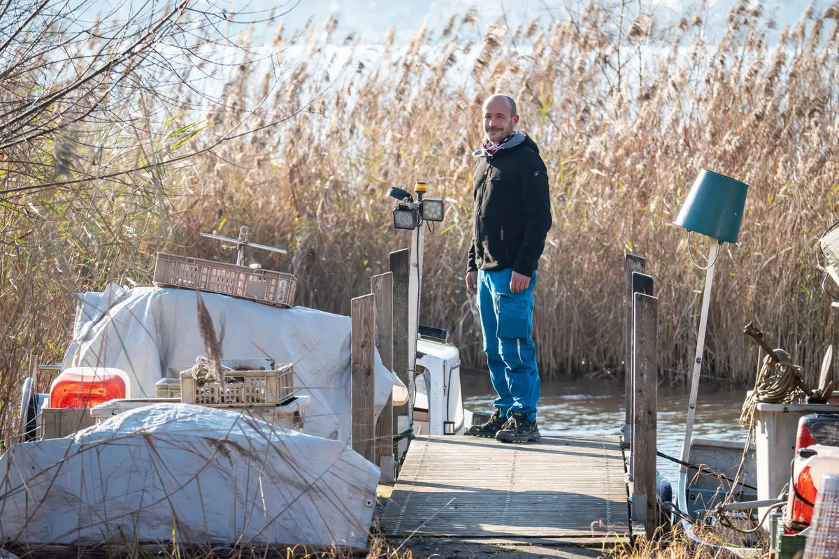 «Der See hat mich Demut gelehrt. Ich kann nichts erzwingen, sondern muss das annehmen, was er mir bietet»: Für Samuel Weidmann ist der See auch ein «Kraftort». Berufsfischer Samuel Weidmann steht am Ende seines Bootsstegs in Stäfa. Links ist sein Motorboot zu sehen, im Hintergrund ein Schilfgürtel.